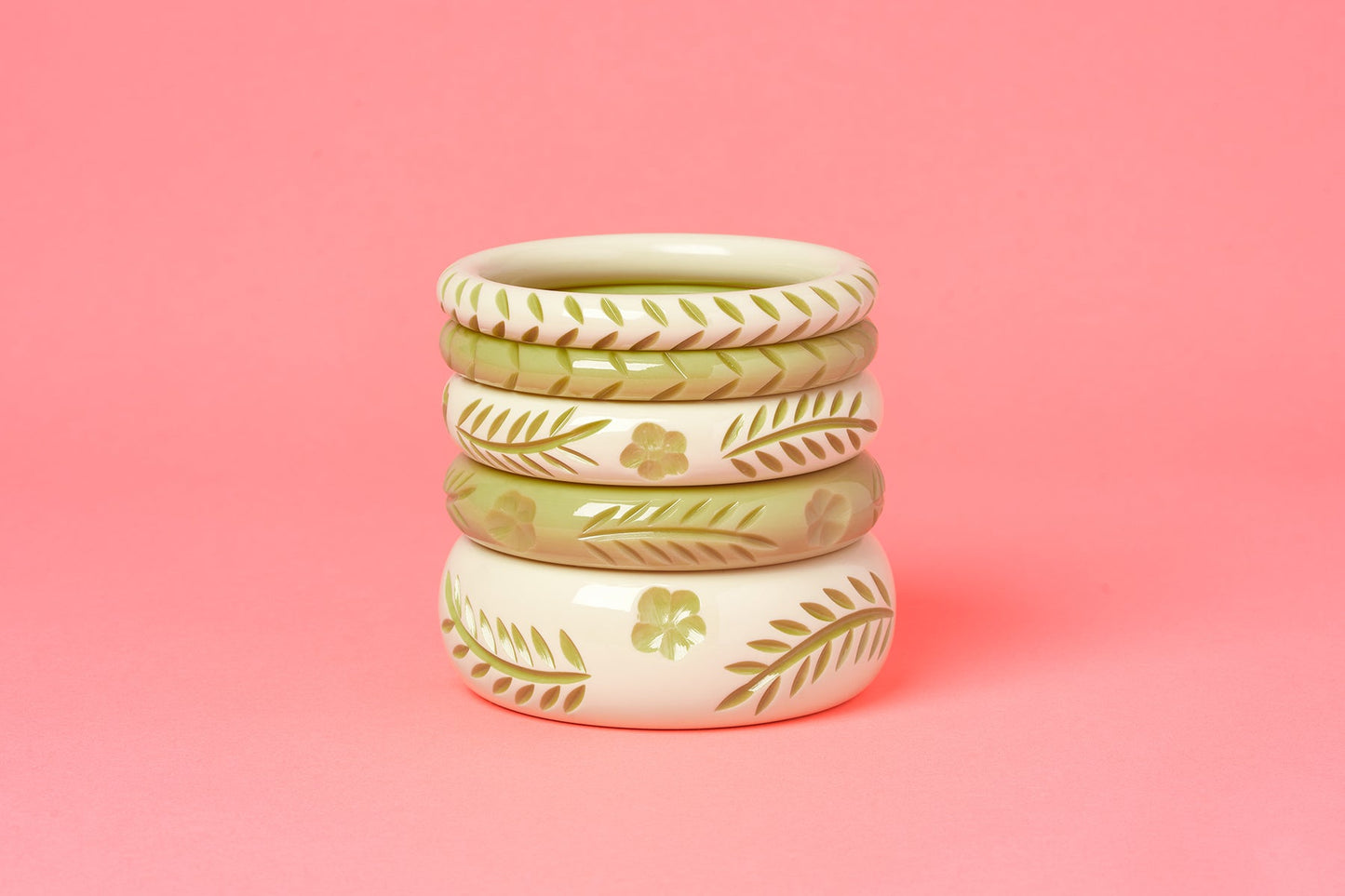 Splendette vintage inspired 1940s Bakelite style carved pastel green fakelite Rowan and Rowan Cream Bangles on a coral pink background
