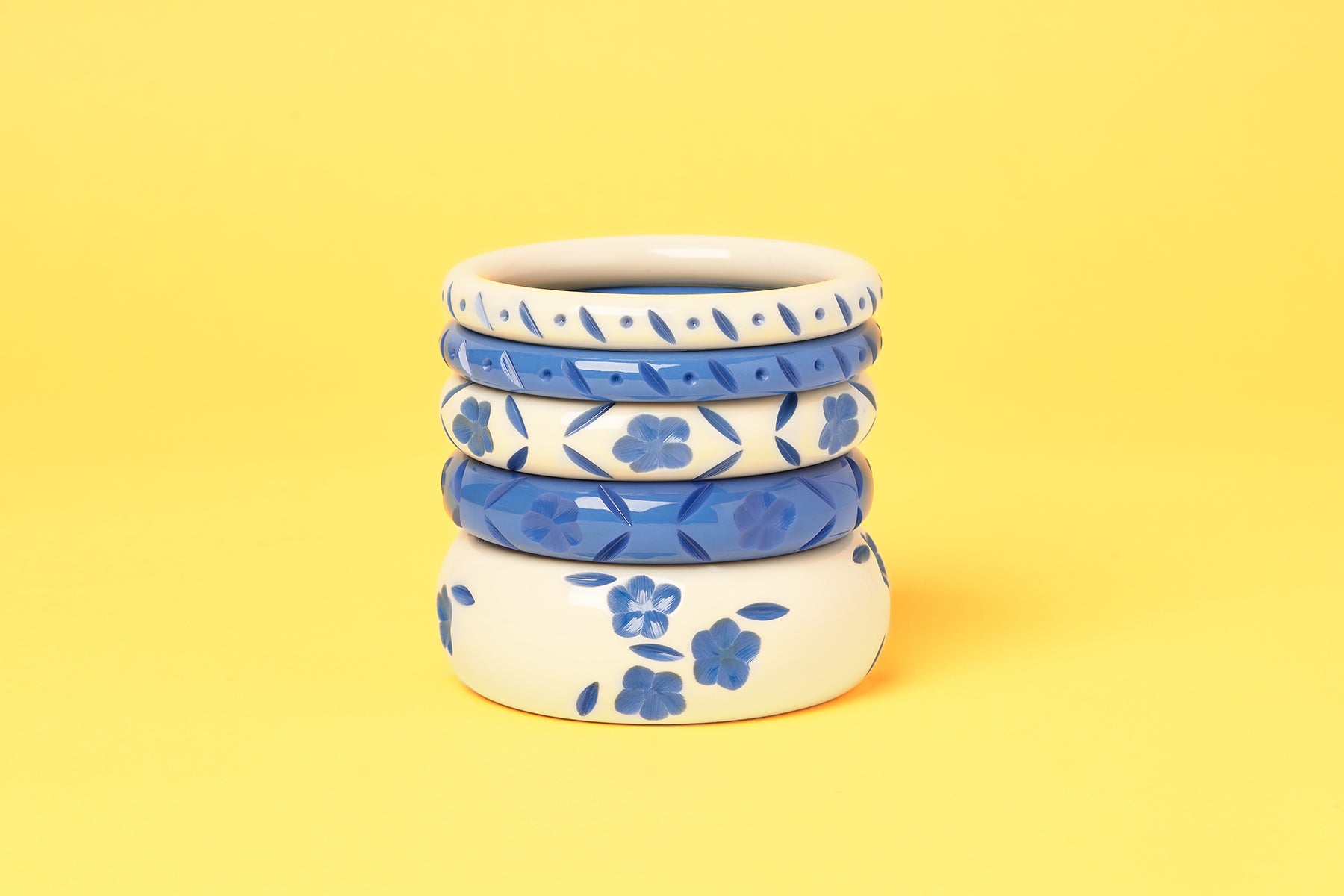 Splendette vintage inspired 1940s style carved blue fakelite Veronica and Veronica Cream Bangles on a yellow background