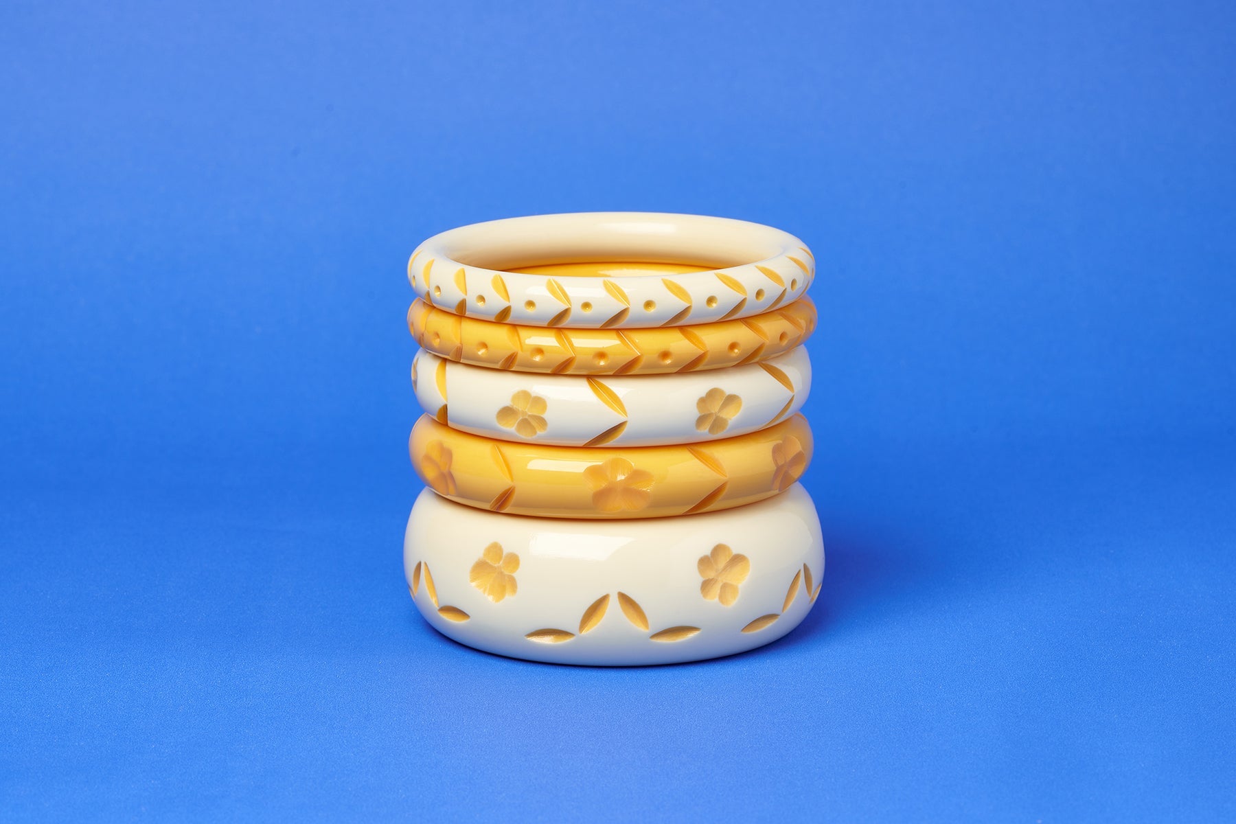 Splendette vintage inspired 1940s style carved yellow pastel fakelite Primrose and Primrose Cream Bangles on a blue background